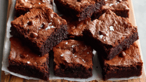 Indulge in a Gluten Free Zucchini Brownies Recipe that blends rich chocolatey flavor with the hidden goodness of zucchini. This recipe delivers moist, fudgy brownies without compromising on taste or texture, making it perfect for family gatherings, holiday treats, or a guilt-free dessert fix. Whether you are gluten-intolerant, health-conscious, or just seeking a delicious twist on a classic dessert, these brownies promise comfort and satisfaction in every bite.  Why You’ll Love This Gluten Free Zucchini Brownies Recipe  Moist & Fudgy Texture: Zucchini adds natural moisture, keeping brownies soft and chewy.  Healthy Swap: Gluten-free flours and almond butter create a nutrient-packed indulgence.  Rich Chocolate Flavor: Cocoa powder and chocolate chips enhance the dessert without overpowering.  Quick & Easy: Simple ingredients and minimal prep make this a weeknight-friendly treat.  Kid-Friendly: Sneak in vegetables without them noticing.  Diet-Friendly Options: Adaptable for paleo, keto, or dairy-free variations.  Budget-Friendly: Common pantry ingredients make this recipe economical.  Make Ahead: Freezes beautifully for later enjoyment.  Ingredients
Wet Ingredients  1 cup almond butter  1/4 cup pure maple syrup  2/3 cup coconut sugar or brown sugar  2 large eggs, at room temperature  2 teaspoons vanilla extract  Dry Ingredients  1/3 cup + 2 tablespoons unsweetened cocoa powder  1 teaspoon baking powder  1/4 teaspoon salt  Additional Ingredients  1 1/2 cups finely grated zucchini, undrained (about 1 medium zucchini)  3/4 cup semi-sweet chocolate chips, divided  Pro Tips on Ingredients:  Almond butter adds healthy fats and binds ingredients naturally.  Coconut sugar balances sweetness and supports browning.  Grated zucchini should not be squeezed; moisture is crucial for fudginess.  Chocolate chips can be substituted with vegan or sugar-free options for dietary needs.  Step-by-Step Instructions
1. Prepare the Zucchini  Grate zucchini finely and leave the moisture intact. Removing seeds ensures smooth texture. This natural hydration helps create the soft, fudgy consistency that makes this Gluten Free Zucchini Brownies Recipe irresistible.  2. Mix Wet Ingredients  Preheat your oven to 350°F (175°C). In a large bowl, whisk together almond butter, maple syrup, coconut sugar, eggs, and vanilla extract until smooth. This step emulsifies the fats and sugars, creating a creamy batter base.  3. Add Dry Ingredients  Sift cocoa powder into the mixture, then fold in baking powder and salt. Sifting prevents lumps and ensures even distribution, enhancing texture and flavor.  4. Fold in Zucchini  Gently incorporate the zucchini into the batter until evenly combined. The zucchini acts as a natural moisture enhancer, giving the brownies their fudgy core.  5. Bake  Pour batter into a lined 8×8 inch baking pan. Sprinkle 1/2 cup chocolate chips on top for melty chocolate pockets. Bake for 25–28 minutes, until edges are set but the center remains slightly undercooked for optimal gooeyness.  6. Cool and Serve  Let the brownies cool completely before slicing to allow flavors and textures to meld. The chocolate chips solidify, giving the perfect bite every time.  Pro Tips for Perfect Gluten Free Zucchini Brownies
How can I make my brownies extra fudgy?  Use finely grated zucchini without squeezing it and slightly underbake the center. This retains moisture and gives a decadent texture.  Can I substitute almond butter?  Yes, peanut butter or sunflower seed butter works. Adjust sweetness slightly to balance flavor.  Can I make this dairy-free?  Absolutely. Stick to non-dairy chocolate chips and ensure cocoa powder is unsweetened.  Best Ways to Serve  Top with a scoop of vanilla ice cream for a classic dessert twist.  Drizzle with melted dark chocolate or caramel sauce.  Serve as bite-sized snacks at parties.  Related Recipes:  Classic Gluten-Free Chocolate Chip Cookies Recipe  Vegan Banana Bread Recipe  Nutrition (Per Serving, 12 Servings)  Calories: 190 kcal  Protein: 4g  Carbs: 18g  Fat: 12g  Fiber: 3g  Sugar: 10g  Daily Values: Vitamin A 2%, Vitamin C 3%, Calcium 4%, Iron 8%  Storage & Leftovers  Room Temperature: Airtight container for up to 3 days.  Refrigerator: Up to 1 week; bring to room temp before serving.  Freezer: Wrap tightly in foil or freezer-safe container for 2–3 months.  Reheating Tip: Microwave for 15–20 seconds to revive fudginess.  FAQs  Q: How do I prevent zucchini from making brownies soggy?
A: Use finely grated zucchini and fold gently. Slightly underbaking helps set the brownies without drying them.  Q: Can I make this recipe nut-free?
A: Yes, substitute almond butter with sunflower seed butter and ensure all ingredients are nut-free.  Q: Are these brownies suitable for kids?
A: Definitely. The zucchini adds hidden nutrition, and the chocolate makes it kid-friendly.  Q: Can I add extra flavors?
A: Vanilla, cinnamon, espresso powder, or orange zest complement the chocolate flavor wonderfully.  Variations  Paleo-Friendly: Use coconut flour and honey instead of almond butter and coconut sugar.  Chocolate Lovers: Mix in dark chocolate chunks for a richer flavor.  Low-Carb: Substitute coconut sugar with erythritol or monk fruit sweetener.  Seasonal Twist: Add pumpkin puree in fall or berries for summer variations.  Conclusion & Social CTA  Unlock the hidden magic of zucchini in your dessert with this Gluten Free Zucchini Brownies Recipe. Rich, fudgy, and naturally sweetened, it’s a treat you can feel good about sharing. Try it tonight, snap a pic, and tag your friends—your new favorite dessert is just a bake away!